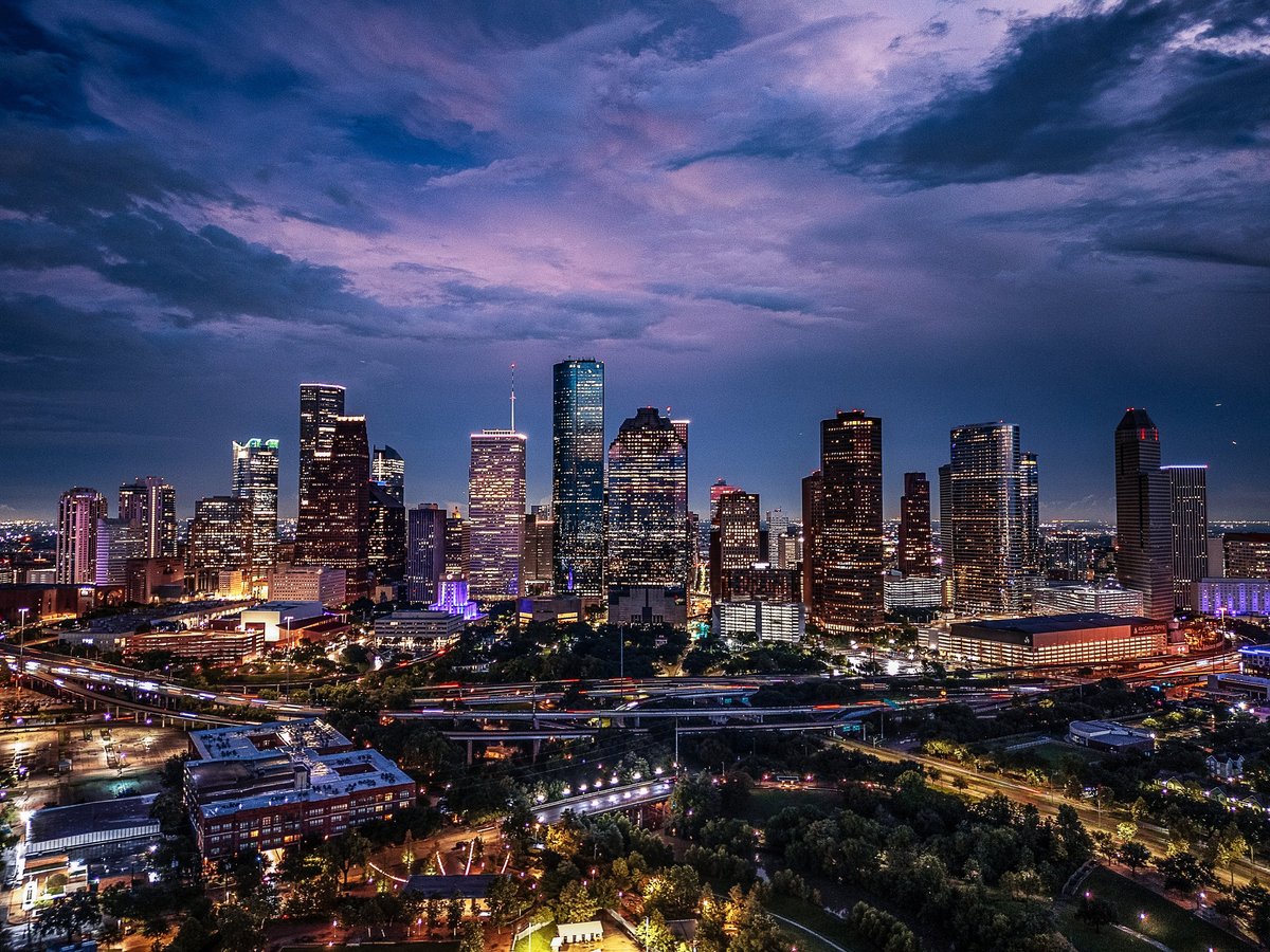 Drone aerial image of downtown Houston, Texas captured at twilight. Illuminated skyscrapers and cityscape under a dramatic evening sky.