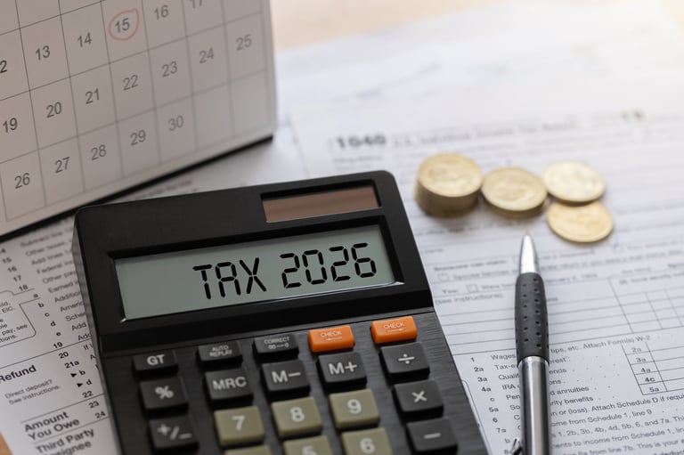Annual tax planning concept with calculator displaying TAX, stacks of coins, a calendar, and a pen on a wooden desk — ideal for tax deferral and financial strategy.
