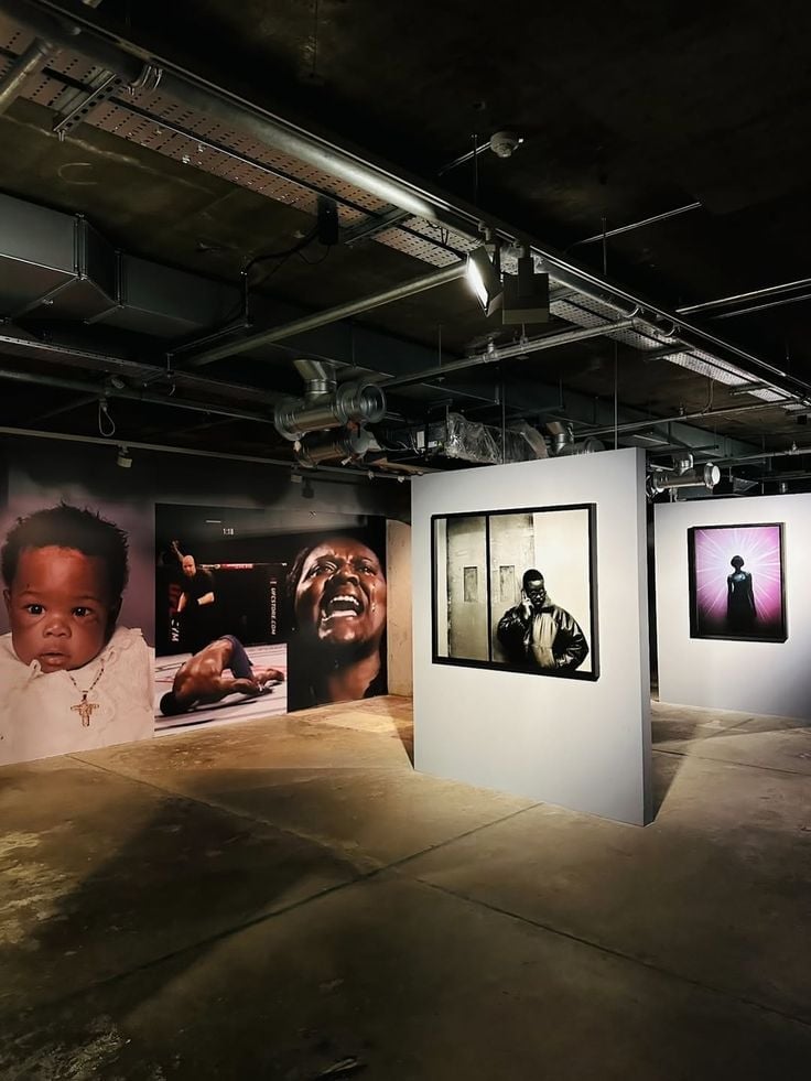 Modern art gallery interior with large photographic portraits on white walls and exposed ceiling with industrial lighting
